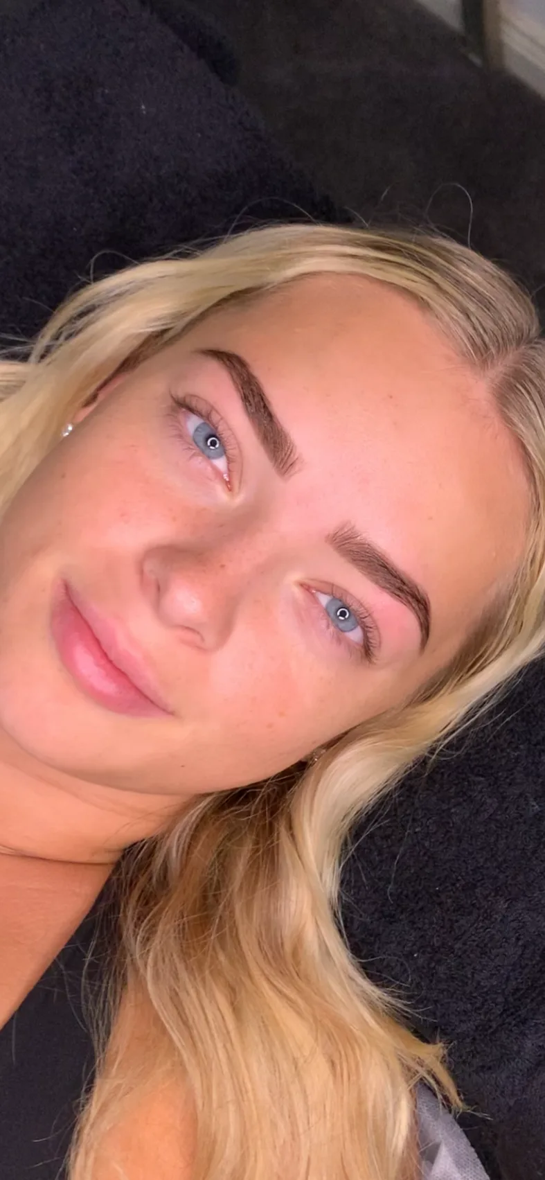 A client resting on the treatment bed after a brow sculpt, the shape sitting square to the eye.