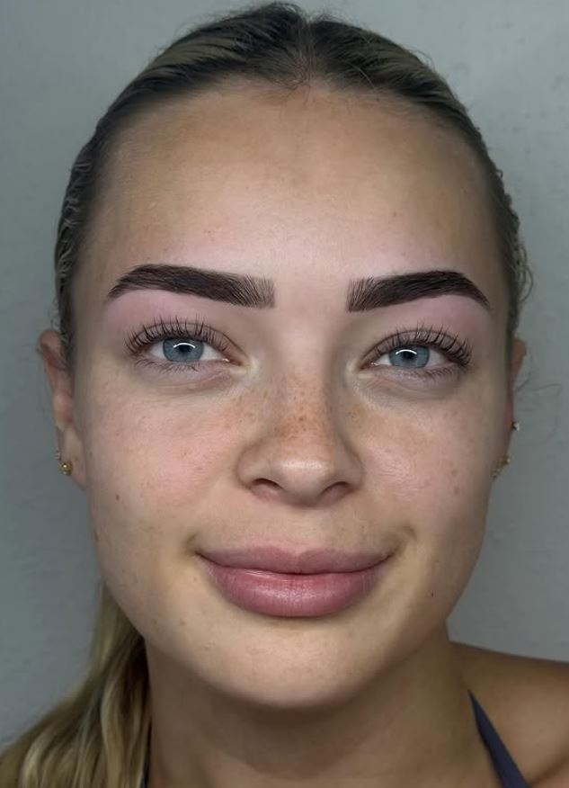 A client facing the camera after a brow sculpt and tint, brows shaped and evenly defined.
